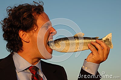 Angry businessman eating fish Stock Photo