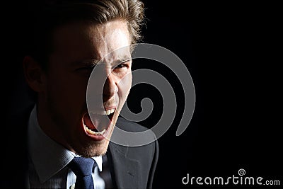 Angry businessman shouting isolated in black Stock Photo