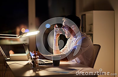 Angry businessman with smartphone at night office Stock Photo