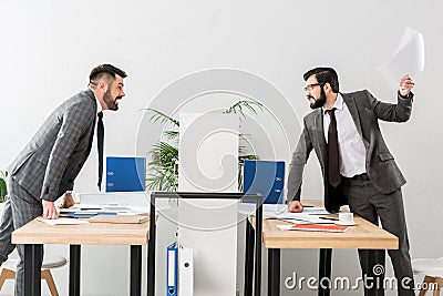 angry businessmen quarreling above partition Stock Photo