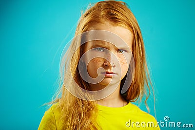 Angry children girl with red hair on blue. Stock Photo
