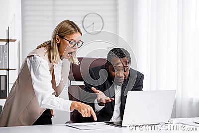 Angry female boss scolding African American office worker. A demanding manager-leader is annoyed by laziness and Stock Photo