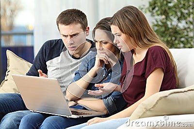 Angry friends watching content on a laptop Stock Photo