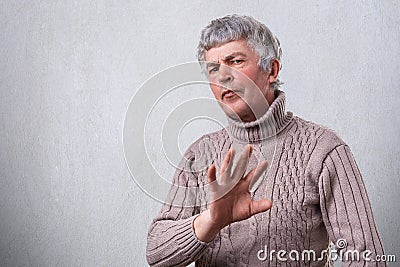 An angry frowning mature man having negative expression showing refusing sign with palm. Negative human emotion face expression fe Stock Photo