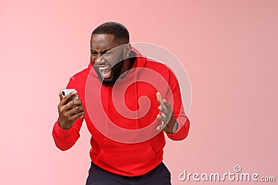 Angry furious african-american bearded guy lose control emotions shouting outraged annoyed smartphone display look phone Stock Photo