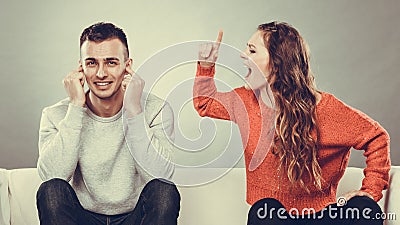 Angry fury woman screaming man closes his ears. Stock Photo