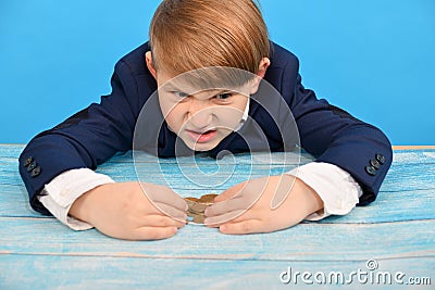 The angry and greedy boy covered the coins with his hands and does not give them to anyone Stock Photo