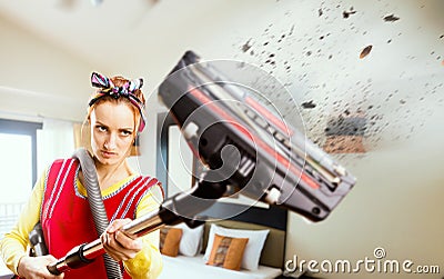 Angry housewife in apron with vacuum cleaner Stock Photo