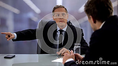 Angry male chief pointing exit to male candidate during job interview, fail Stock Photo