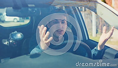 Angry man driving a vehicle arguing and gesturing shaking his hands perplexed. Irritated and furious driver guy negative facial Stock Photo