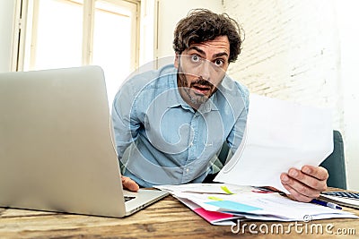 Angry man paying bills as home with laptop and calculator Stock Photo