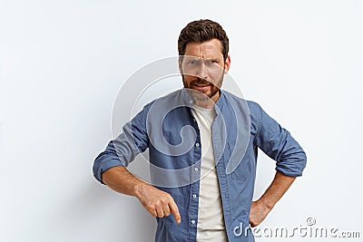 Angry man points finger down and say to you come here right now while standing on white background Stock Photo