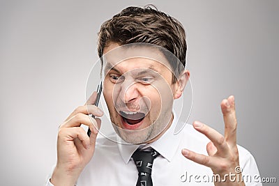Angry man screaming on client by phone. Aggressive boss calling employee who didn`t finish his work on time. Stock Photo