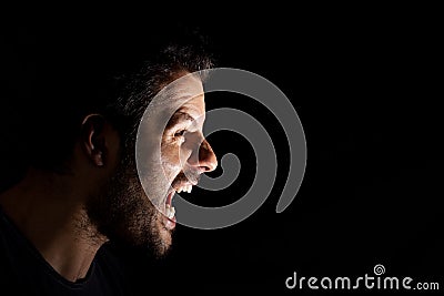 Angry man shouting out loud isolated on black background Stock Photo