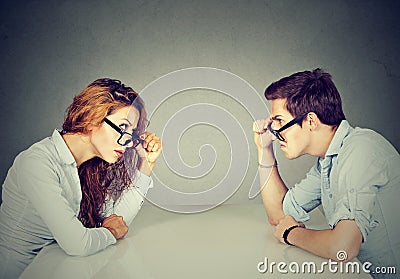 Angry man and woman sitting at table looking at each other with hatred and disgust Stock Photo