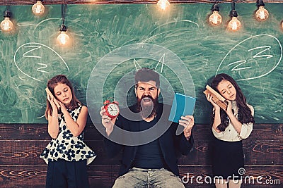 Angry man with alarm clock and book. Little girls students tired of study in school. Monster teacher shout at sleepy Stock Photo