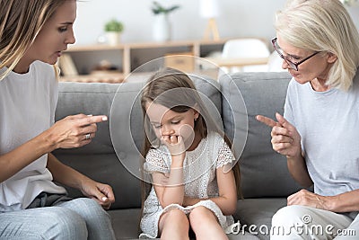Angry mother and grandmother scolding lecturing upset kid girl t Stock Photo