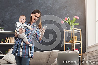 Angry mother holding baby while using phone Stock Photo