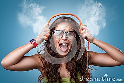 Angry nervous girl in headphones listening to music Stock Photo