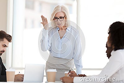 Angry powerful mature boss scolding employees at group corporate Stock Photo