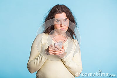 Angry and resentful woman waiting for excuses and explanations and is reproachfully looking on blue background. Stock Photo