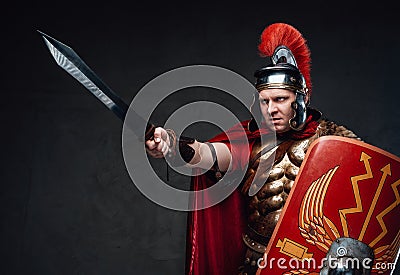 Angry roman soldier points sword against dark background Stock Photo