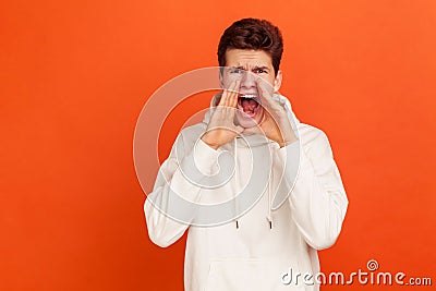 Angry scared teenager in casual white hoodie loudly screaming widely open his mouth, furious male defending his opinion Stock Photo