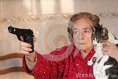 Angry senior woman protecting her cat with a gun Stock Photo