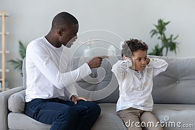 Angry single black father scolding stubborn fussy little african son Stock Photo