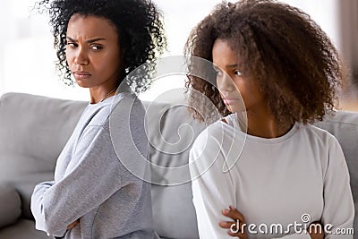 Angry stubborn african mother and teen sitting back turned away Stock Photo