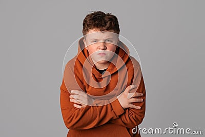 Angry suspicious teenager boy standing in closed posture as sign of protection, holding arms crossed on his chest. Grumpy and Stock Photo