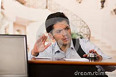 Angry and tired guest touching the bell of the recepcionist Stock Photo