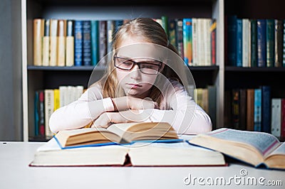 Angry and tired schoolgirl studying with a pile of books Stock Photo