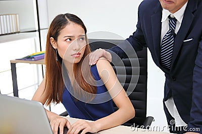 Angry unhappy Asian secretary woman looking hand`s boss touching her shoulder in workplace. Sexual harassment in office Stock Photo