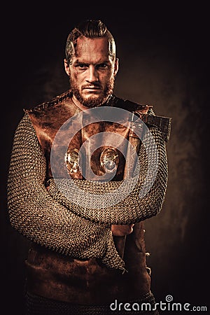 Angry viking in a traditional warrior clothes, posing on a dark background. Stock Photo