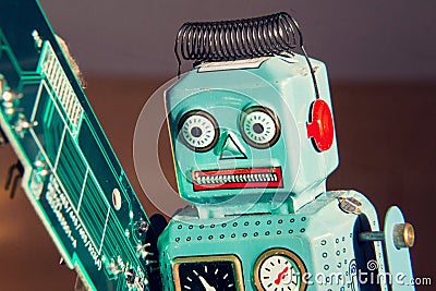 Tin toy robot carries computer circuit board, artificial intelligence concept Stock Photo