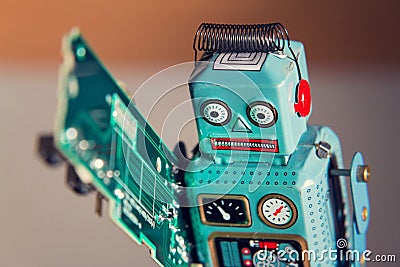 Tin toy robot carries computer circuit board, artificial intelligence concept Stock Photo