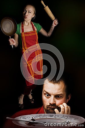 Angry wife with kitchen tools and hungry husband Stock Photo