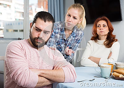 Angry wife and mother-in-law rebuking young man Stock Photo