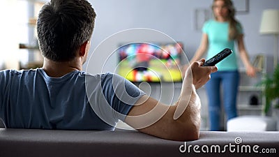 Angry wife quarreling with husband watching football game, conflict in relations Stock Photo