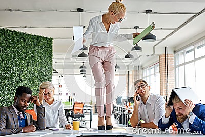 Angry woman boss criticizing frustrated employees at work place Stock Photo