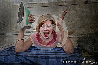 Angry woman or crazy busy housewife ironing shirt lazy at home kitchen using iron Stock Photo