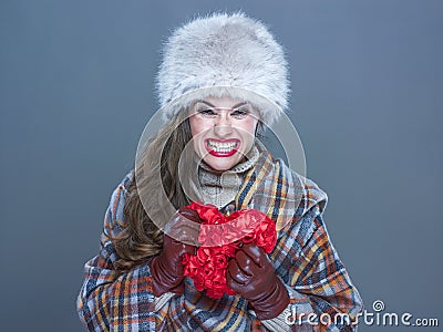 Angry woman isolated on cold blue background crushing red heart Stock Photo