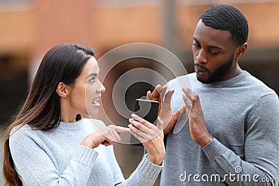 Angry woman scolding a man showing phone content Stock Photo