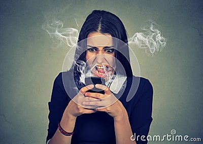 Angry woman shouting at her cell phone, enraged with bad service Stock Photo