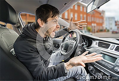 Angry young driver is driving a car and shouting Stock Photo