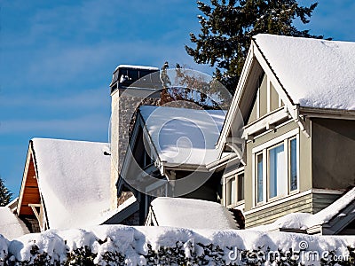 Snow covered roofs of residential dwellings against blue skies Stock Photo
