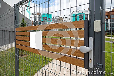 Angular view of metal gates with blank tablet on wooden planks Stock Photo