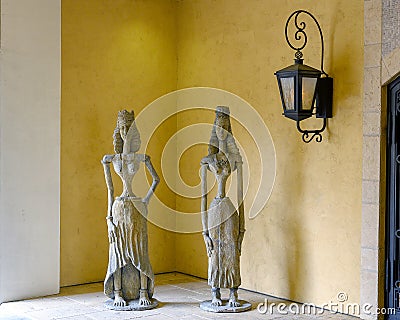 Anicent stone sculptures of female royalty stadning in Dallas, Texas, beside a gothic style wall lamp. Editorial Stock Photo