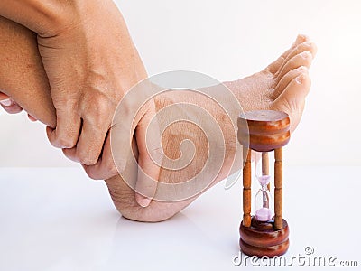 Ankle pain and hurt feet, sore foot of Asians with hourglass, Concept of time and foot health care Stock Photo